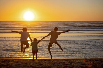 Happy children, boys, playing on the beach on sunset, kid cover in sand, smiling, laughing