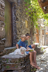Beautiful medieval village Talasnal in Lousa, Portugal on a beautiful day. Child playing on the street of the village with his pet dog