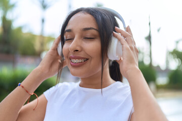 Young arab woman smiling confident listening to music at street