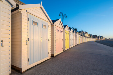 Colourful beach huts, running into the distance, set against a blue, summers sky. The location is Lyme Regis, on the south coast of England