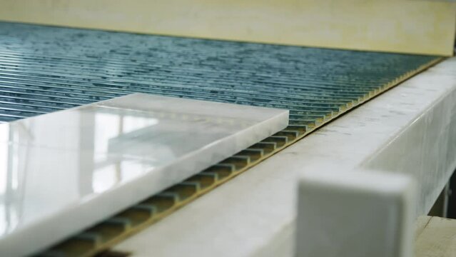 Close up no people shot of moving conveyor belt with marble tile on production line at natural stone factory