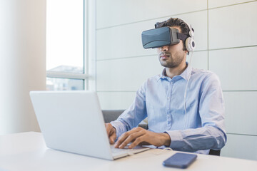 Young indian businessman using 3D viewer and pc