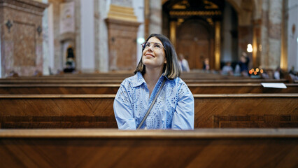 Young beautiful hispanic woman sitting on a church bench at St. Karl BorromÃ¤us church