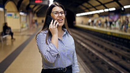 Young beautiful hispanic woman waiting for the subway speaking on the phone in subway station of Madrid