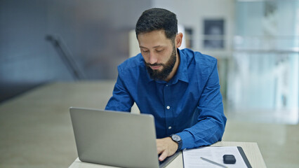 Young hispanic man business worker using laptop working at the office