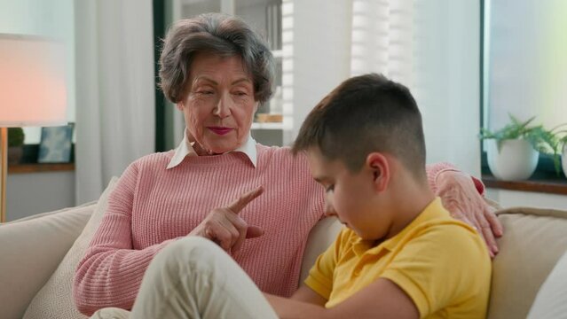 Serious strict grandmother scolding offended grandson at home couch senior woman grandma punishing disobedient grandchild kid boy bad behavior demand discipline explain family conflict two generation