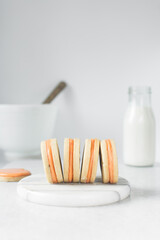Fototapeta na wymiar Vanilla sugar cookies with orange filling, round rosemary cookies filled with orange cream, no spread cookies on a marble tray with a white background