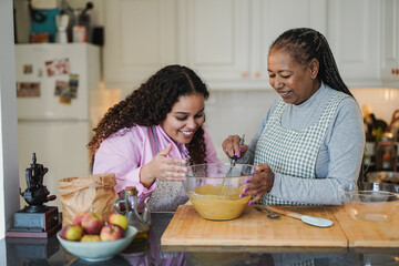 Happy african mother and daughter preparing fresh cake in the morning inside house kitchen