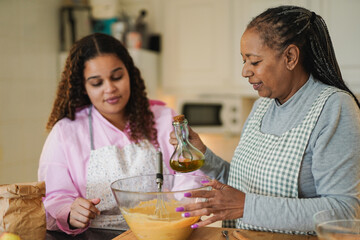 African mother and adult daughter preparing fresh cake together at home kitchen