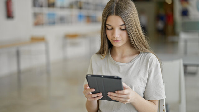 Young beautiful girl student using touchpad studying at library