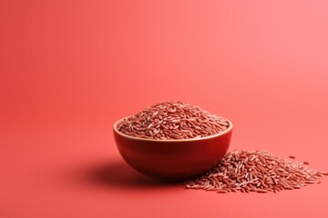 Red rice in bowl on red background.