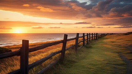 coast landscape with fence and meadow near the sea at sunset