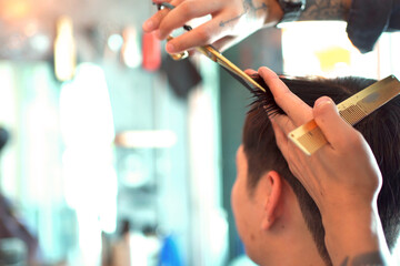 Handsome Asian man having a haircut at street hairdresser shop, professional street hair dresser -...