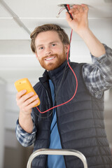 Fototapeta premium man measuring and cheking power supply voltage with digital multimeter