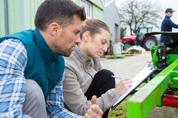 woman with blueprint and clipboard talking to colleague