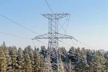 Electric Power Transmission Tower on the Background of a Winter Coniferous Forest