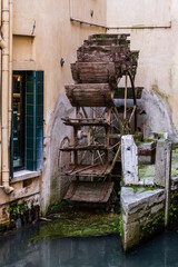 Fototapeta na wymiar Altes geschichtsträchtiges Wasserrad, auf dem sich eine Taube niedergelassen hat in einem alten Städtchen Italiens
