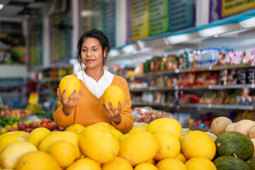 Brazilian woman chooses melon in supermarket.