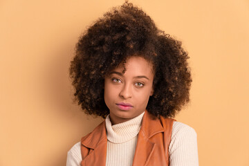 annoyed afro brazilian woman looking at camera in beige studio background. frustration, unhappy,...