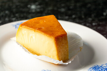 pudding or pudim slice, on a white plate and black background. gourmet or homemade delicious pudding also known as flan