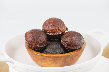 Unniyappam or Unni appam - Traditional kerala deep fried snack with rice dry coconut jaggery ghee , selective focused image. Unniyappam in a wooden bowl and isolated background