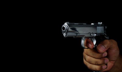 Male hand holding a gun on black background . Pistol in a man's hand. defense or attack murderer or...