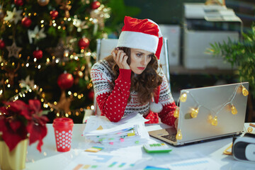business woman in green office with Christmas tree working
