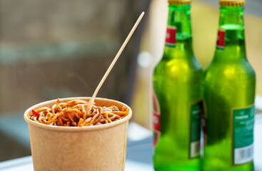 Chinese takeaway food. Wok with noodles and bottles with cold beer.