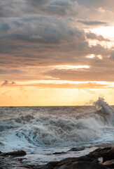 Beach waves crashing on rocks during sunset