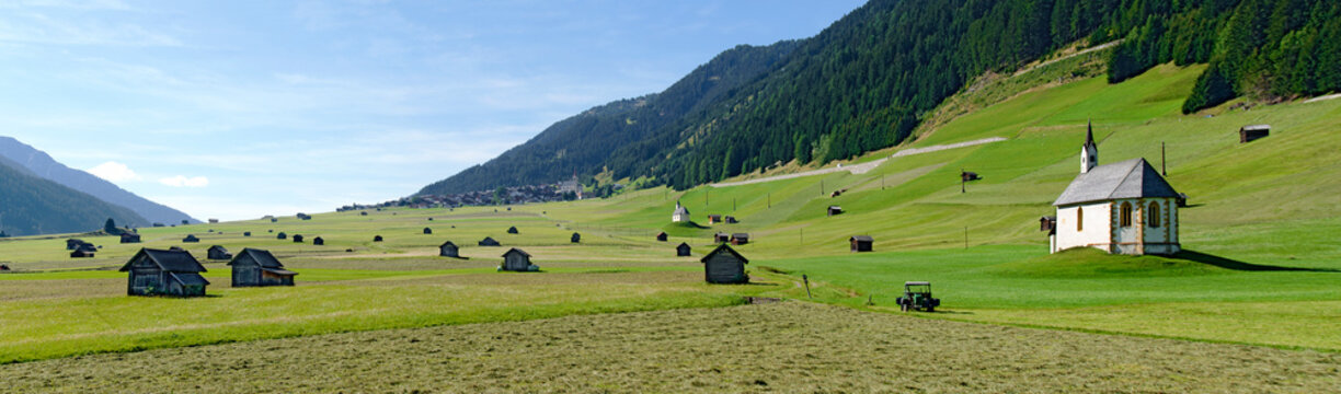 panoramic view across a meadow slope with old wooden huts and little chapels in the Gailvalley of Eastern Tirol, Austria