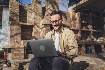 man caucasian work on laptop computer on terrace happy smile success