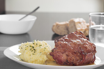 Pork knuckle with mashed potatoes with bread and glass with water