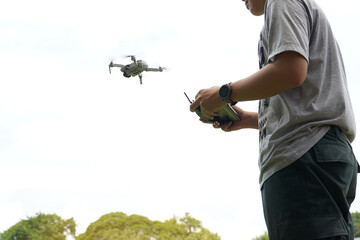Thai students control the flight of a drone or unmanned aerial vehicle with a joystick. to explore and take high-angle photos of the interior of the school. Soft and selective focus.