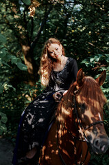 Fototapeta premium Portrait of young beautiful woman riding brown horse