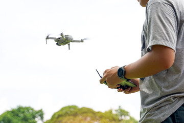 Thai students control the flight of a drone or unmanned aerial vehicle with a joystick. to explore and take high-angle photos of the interior of the school. Soft and selective focus.