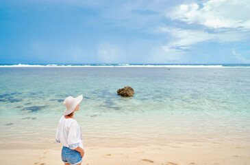 Fototapeta na wymiar Vacation on the seashore. Young woman on the beautiful tropical white sand beach.