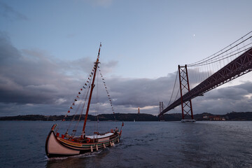 Beautiful landscape with a yacht sailing the Tejo River under the Bridge Ponte 25 de Abril in Lisbon, Prtugal