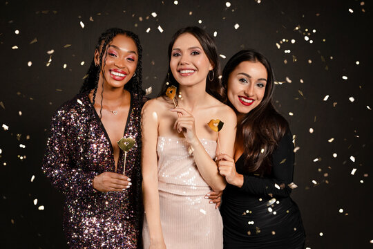 Pretty multiethnic women friends holding photo booth celebrating New Year 2024