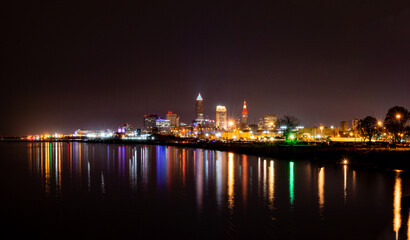 Fototapeta na wymiar A colorful nighttime cityscape of Clevland, Ohio with relectiontions in the still water of Lake Erie