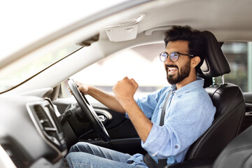 Young emotional indian guy businessman sitting inside luxury car