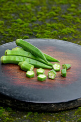 closeup the bunch green lady finger sliced cut piece on the red brown wooden soft focus natural green brown background.