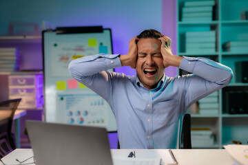 Asian businessman or employee feels like going crazy after hard work and overtime. Asian Male employee who is stressed and tired from working overtime late at night.