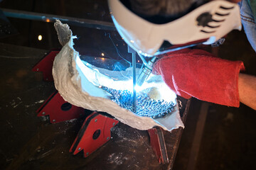 Anonymous craftsman welding metal pieces in garage