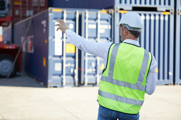 back view factory worker or engineer looking forward and pointing pose in containers warehouse storage