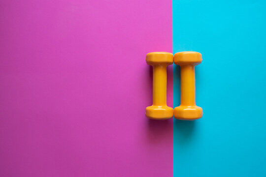 Two dumbbells for sport on the pink blue background.