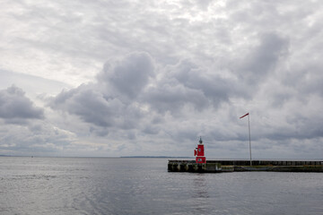 Outdoor exterior view, red lighthouse stand on the shore against overcast sky in Helsingor, Denmark. 