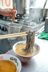 Fototapeta na wymiar Cook preparing tasty dish with noodles and broth