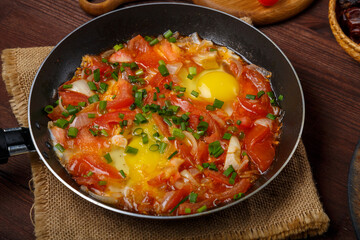 fresh hot shakshuka in a frying pan sprinkled with green onions on a set Shabbat table.