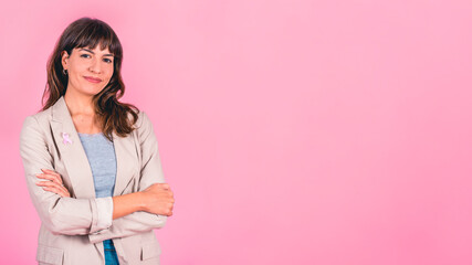 Smiling woman wearing a pink breast cancer awareness ribbon on her coat. Copy space