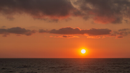 Sunrise from behind the horizon over the seas golden water and sky.